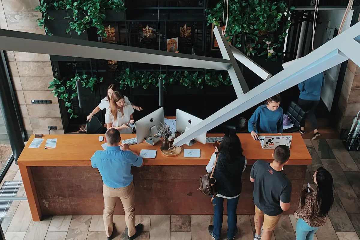 Guests checking in at the front desk of a Valiant Hotels lobby, seen from the mezzanine